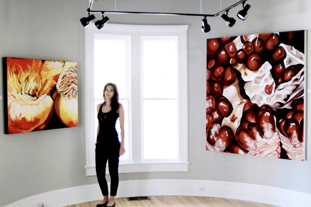 Angela Faustina with her Peach I and Pomegranate V (73) oil paintings during her From the Garden art exhibition at The Rectory in Historic Norcross, Georgia.