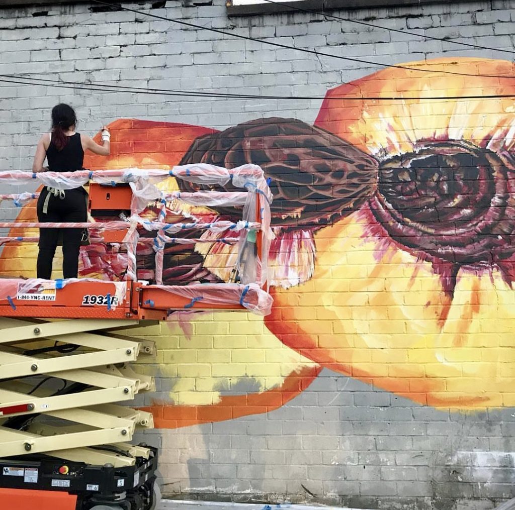 Angela Faustina painting Peach III mural on Marietta Square for the M2R Trailfest, sponsored by Nature's Pick Market.